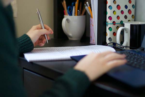 student working at desk holding a pen